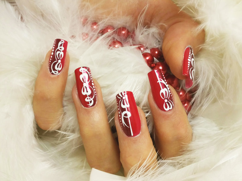 nail art rosso festoso con styline luminosa sottolineata da un fiocco bianco dai nastri sinuosi opera di sara colleoni